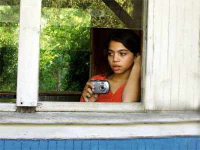 Niña mirando por la ventana del trencito. Con una cámara en sus manos.