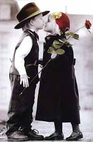 Ni&ntilde;o y ni&ntilde;a vestidos de adultos con una flor.